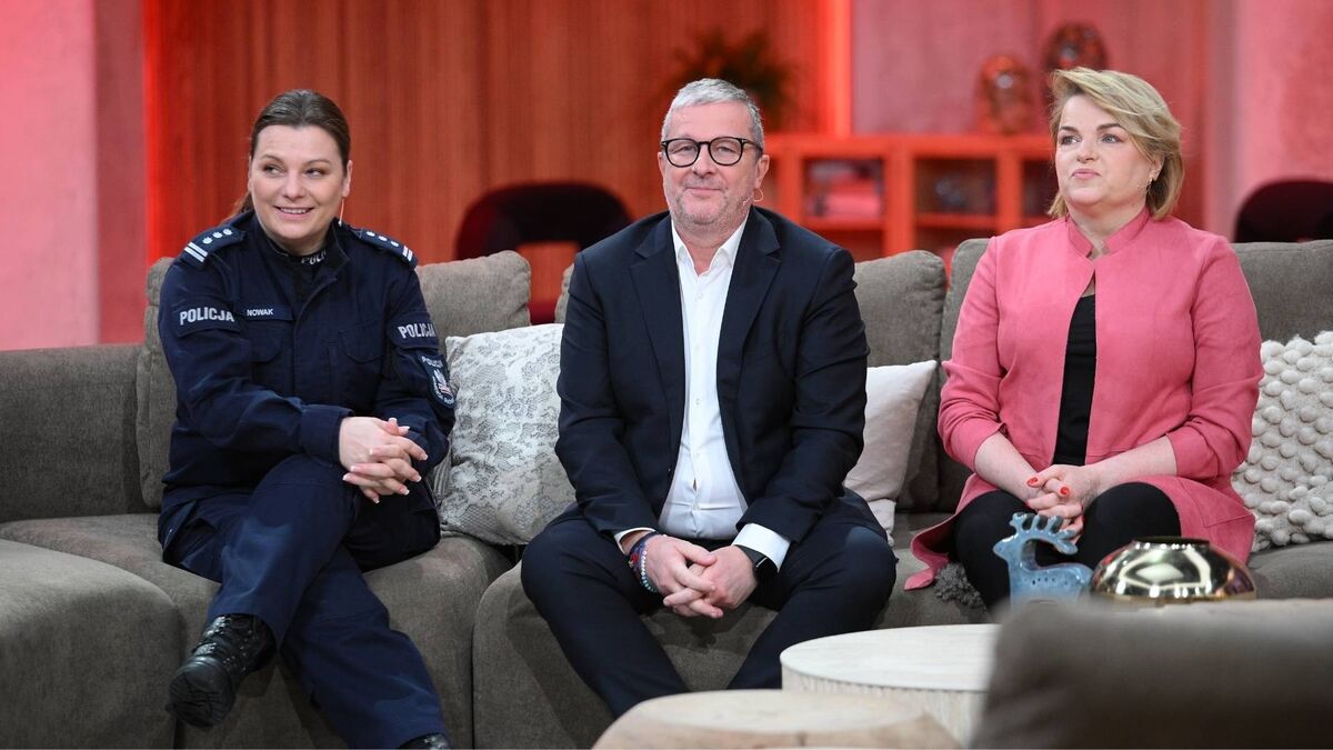 Katarzyna Nowak, Przemyslaw Barbrich, Katarzyna Bosacka siedzą na kanapie w studiu telewizyjnym podczas rozmowy w programie na żywo. Po lewej stronie widać kobietę w policyjnym mundurze, w środku mężczyznę w garniturze i okularach, a po prawej kobietę w różowej marynarce. W tle znajduje się ciepło oświetlona scenografia z półkami i dekoracjami, a przed nimi stoi stolik z ozdobnymi przedmiotami.